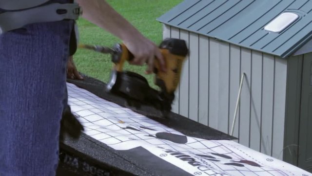 A man nails down a roofing tile trim.