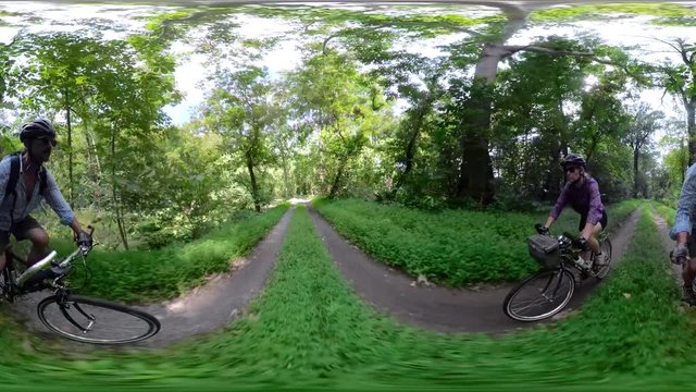 4K 360 vr of mature man and woman bicycling on dirt on a sunny day in a forested C&O Canal National Park.