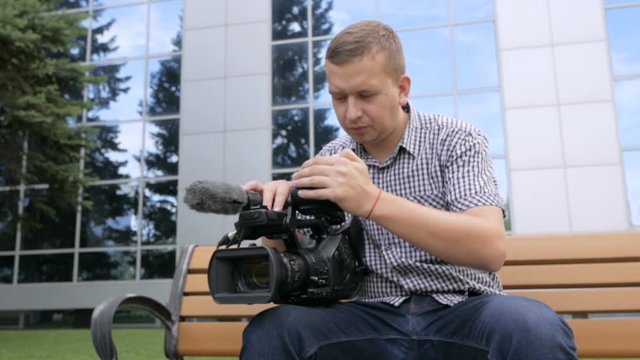 The cameraman sitting on the bench browses the footage in the TV camera