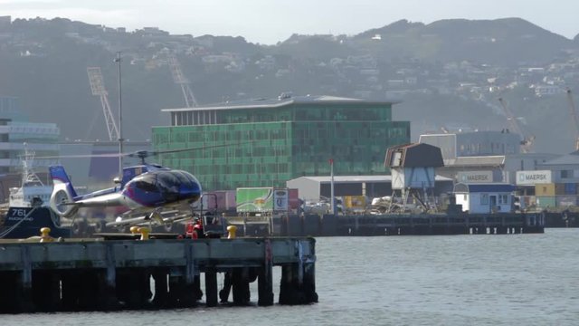 A shot on the Wellington waterfront of a helicopter on a wharf taking off and leaving frame.