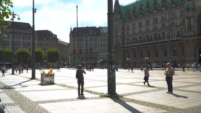 Tourists and kids passing in downtown Hamburg, in front of the townhall