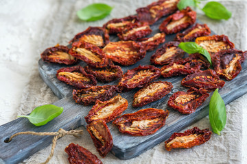 Homemade sun-dried tomatoes on cutting board.