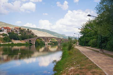 Fototapeta na wymiar Picturesque landscape with old stone bridge. Bosnia and Herzegovina, view of Trebisnjica river, embankment of Trebinje city and Arslanagic ( Perovic ) Bridge