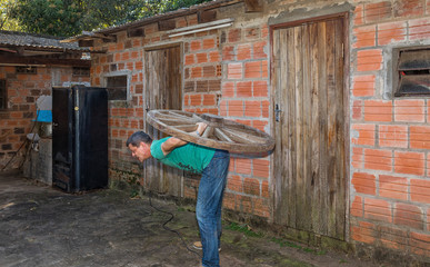 A man carries a wooden wheel on his back.