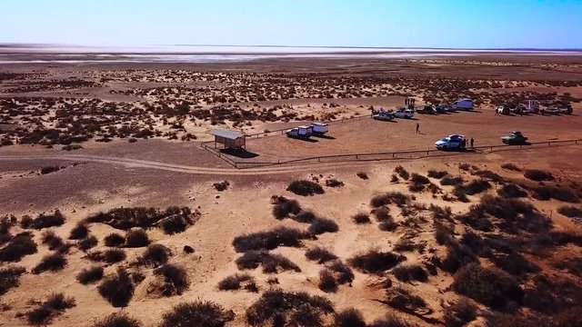 Aerial tracking shot showing tourists visiting the Lake Eyre salt lake in outback South Australia. Very remote area and the lowest natural point in Australia. Near Marree on the Oodnadatta track.