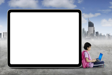 Clever schoolgirl with laptop near whiteboard