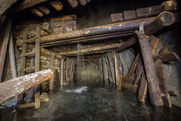 Underground abandoned gold iron ore mine shaft tunnel gallery passage with timbering wooden flooded water