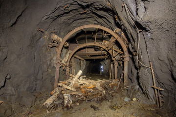 Underground abandoned gold iron ore mine shaft tunnel gallery passage with timbering wooden