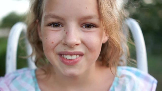 Brown-eyed light-haired girl posing for the camera. first she looks seriously with her big eyes, then she smiles brightly with a white tooth. Changing moods in the child