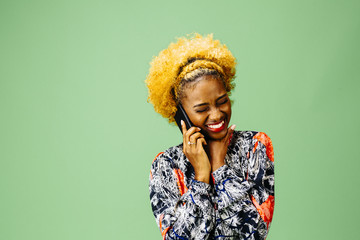 Young woman smiling while talking the phone, isolated on green studio background