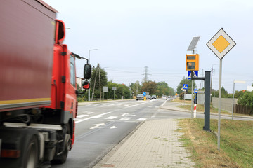 Samochód ciężarowyna na drodze z fotoradarem mierzącym prędkość pojazdów.