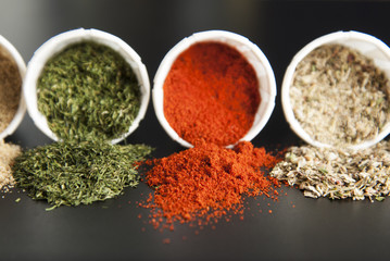 Close up various spices on black background: rosemary, paprika, black pepper.