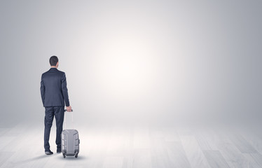 Young businessman in a white boundless space walking with back and luggage on his hand