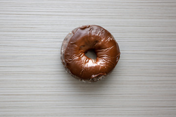 A chocolate donut being eaten and placed on a table from breakfast