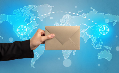 Female hand holding coloured and white envelope with blue map on the background
