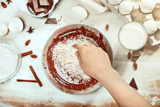 Cropped image of attractive young woman cooking a chocolate pie. Ingridients on white rustik background. Eggs, chocolate, milk, spices. Top view, recipe background.