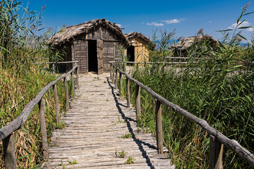 Huts at the reconstructed site of a prehistoric settlement at the Kastoria Lake in Dispilio, Greece  - obrazy, fototapety, plakaty