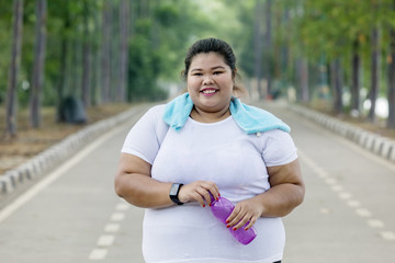 Overweight woman holds bottle of water