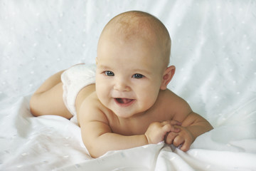 Charming child smiling on a white bed