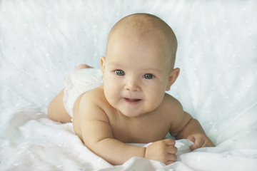 Charming child smiling on a white bed