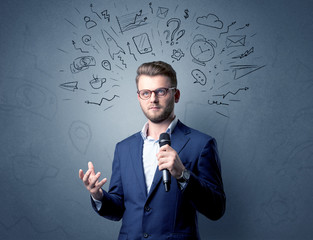 Businessman speaking into microphone with mixed doodles over his head