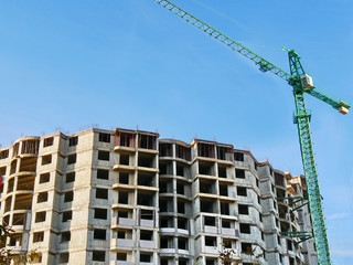 Fototapeta na wymiar Construction site background. Concrete building under construction. Huge crane near building.