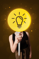 Casual young woman holding round sign with yellow lightbulb