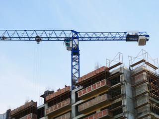 Hoisting crane near building under construction. Construction site background.
