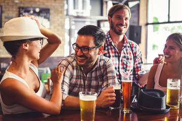 Happy friends having fun at bar - Young trendy people drinking beer and laughing together