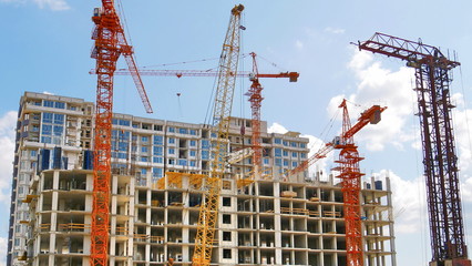 Construction site background. Four hoisting cranes near building.