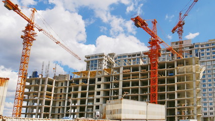 Construction site background. Three huge cranes near concrete building. Building under construction.