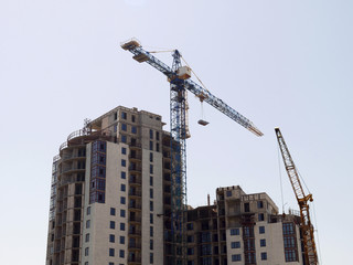 Construction site. Concrete building under construction. Two rower cranes near building.