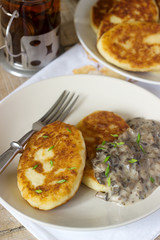 Potato cutlets or pancakes with mushroom sauce and green onions. Rustic style.