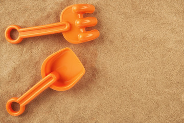 Rake and shovel toy on the beach, directly above. Copy space for your text.