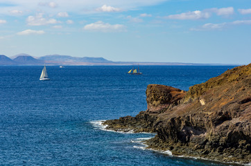 Fototapeta na wymiar Blick von Lanzarote nach Fuerteventura mit zwei Segelbooten und einem Motorboot auf dem Meer