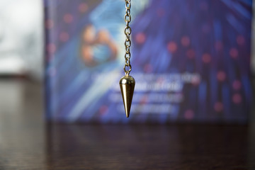 Brass pendulum in front of a book