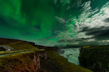 Northern Lights over the Gullfoss waterfall in Iceland. Aurora Borealis in an amazing nightscape. Travel destination with beautiful green lights landscape.