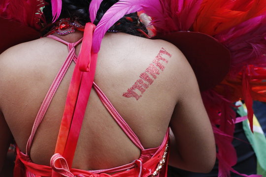 NOTTING HILL, LONDON - AUGUST 27, 2018: Body paint reading "Trinity" on the back of a performer in the Notting Hill Carnival Parade