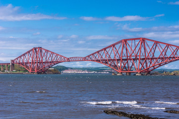 Queensferry, Scotland, UK - June 14, 2012: Closeup of Red metal iconic Forth Bridge for trains over Firth of Forth between blue sky and blue water.