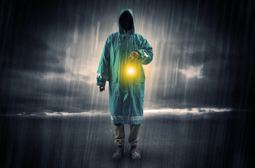 Raincoated man walking in storm with glowing lantern in his hand
