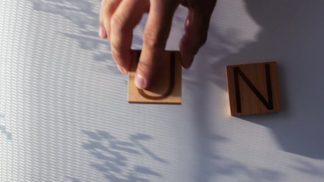 The word "SUN" is laid out in wooden letters