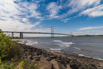 Queensferry, Scotland, UK - June 14, 2012: Forth Road Bridge spans Firth of Forth under blue sky...
