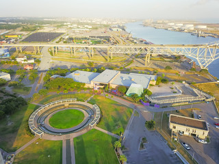Aerial view Harbor Bridge and Water Gardens from Bayfront Science Park in Corpus Christi, Texas, US. Row of white oil tanks and wind turbines farm in distance. Industrial and transportation background