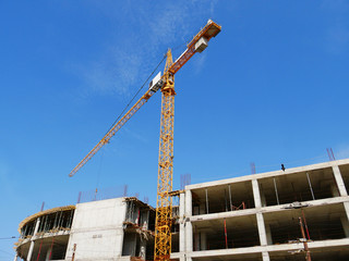 Fototapeta premium Huge crane near concrete building. Construction site.