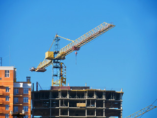 Construction crane near concrete building. Construction site.