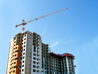 Fototapeta na wymiar Construction of a multi-storey building. Crane and building under construction. Building site.