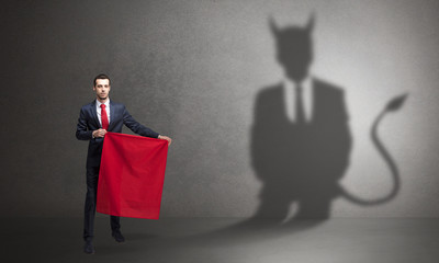Businessman standing with red cloth in his hand and devil shadow on the background
