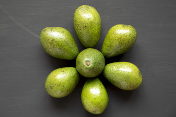 Whole avocados on dark background, overhead view. From above, flat lay.
