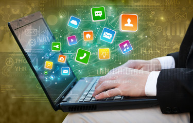 Hand using laptop with bouncing colorful application and global reports and graphs concept
