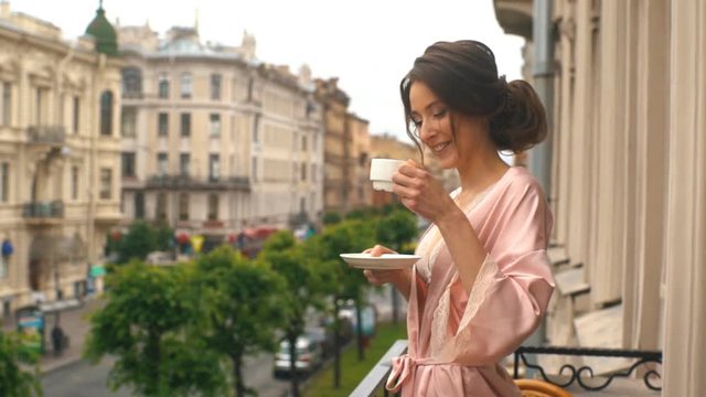 beautiful woman drinking coffee on the balcony of an old house